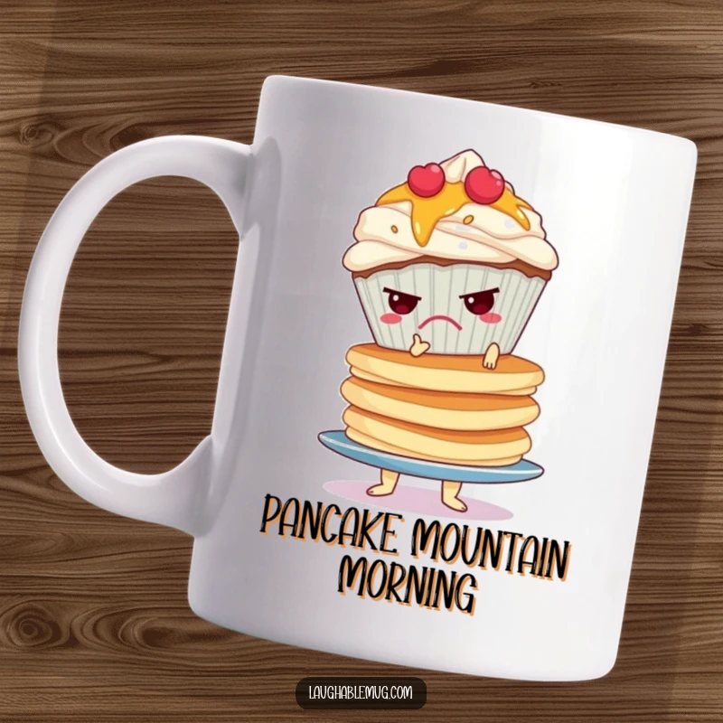 Funny mug showing a grumpy cupcake struggling to balance a tall, wobbly stack of pancakes, embodying morning frustration.