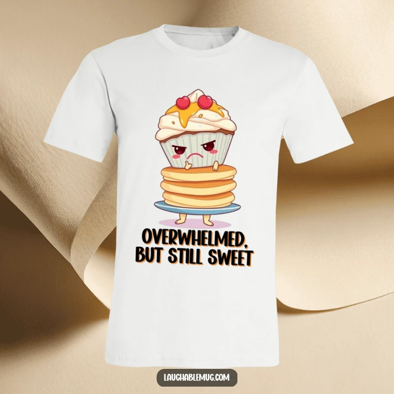 Funny t-shirt featuring a grumpy cupcake precariously balancing a massive, wobbly stack of pancakes, illustrating a stressful situation.